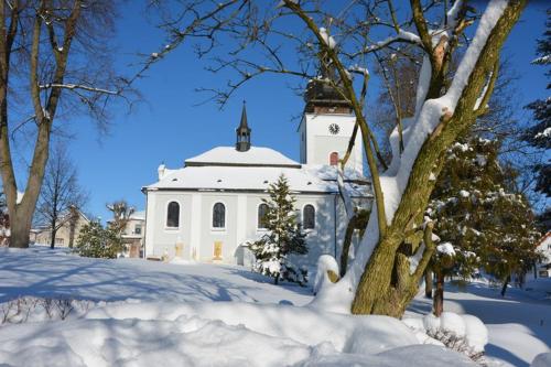 a white building with a steeple in the snow at Chalupa Ivana Bozkov in Bozkov