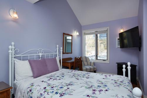 a bedroom with a bed with a floral bedspread at Lady MacDonald Country Inn in Canmore