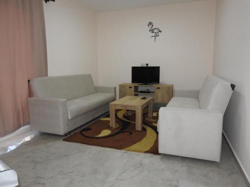 a living room with two chairs and a table and a tv at Alp Apartment in Mağusa
