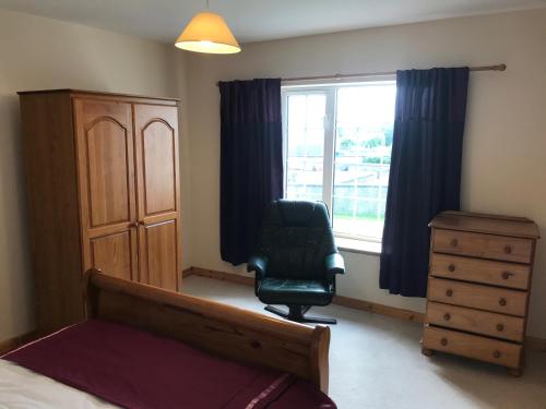 a bedroom with a bed and a chair and a window at 14 Upper Bayble in Stornoway