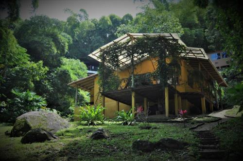 una pequeña casa amarilla con un árbol en Finca Hostal Bolivar - Casa Maracuya, en Minca
