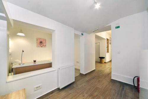Ban Jelačić Apartment في زغرب: ممر به جدران بيضاء وأرضيات خشبية وغرفة بها طاولة