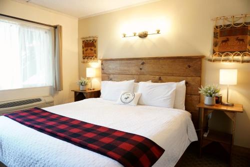 a bedroom with a bed with a plaid blanket on it at Moose Creek Inn in West Yellowstone