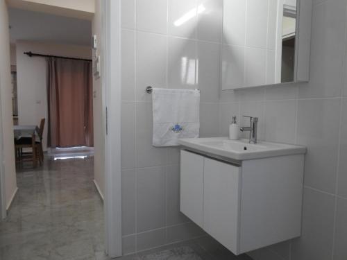 a white bathroom with a sink and a mirror at Alp Apartment in Famagusta