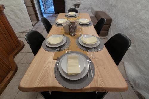 a wooden table with black chairs and plates on it at Guest house Otto in Punat