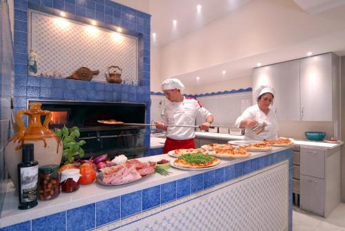 two chefs standing in a kitchen preparing food at Delle Rose Camping & Glamping Village in Isolabona