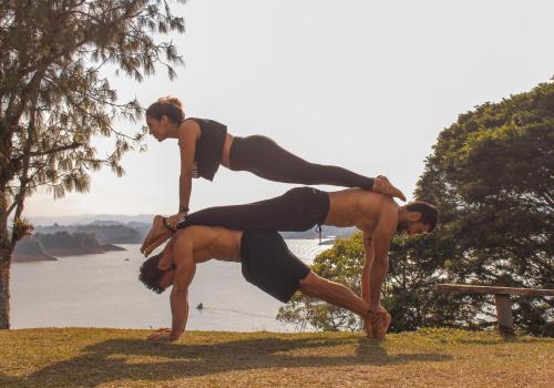 two people are doing a yoga pose by the water at Casa Encuentro Ecolodge, Outdoor Gym and Yoga in Guatapé