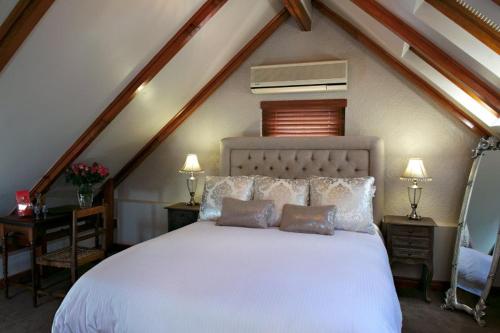 a bedroom with a white bed with two tables and two lamps at Roosenwijn Guesthouse in Stellenbosch