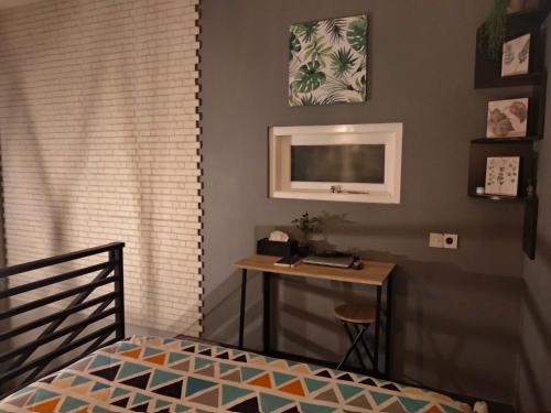 a bedroom with a bed and a desk and a television at Shofiya Guesthouse Solo in Solo