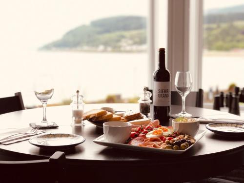 a table with a plate of food and a bottle of wine at St Ives Boutique Hotel in Dunoon