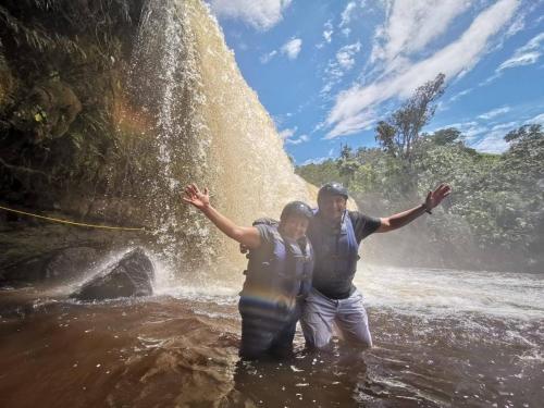 a man and woman standing in the water in front of a waterfall at Hotel El Ganadero in El Total
