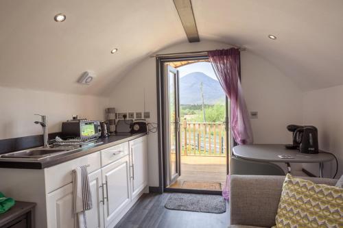 a kitchen with a sink and a door to a balcony at Tigh Beag na h'aibhne in Broadford