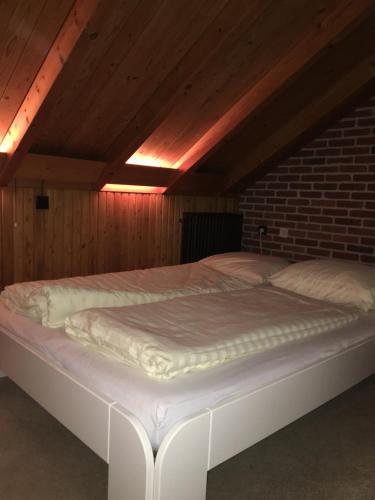 a large white bed in a room with a brick wall at 't Aarthuis in Emst