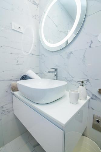 a white bathroom with a sink and a mirror at FK Apartments in Pakoštane