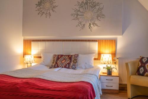 a bedroom with a bed with a red blanket and two lamps at Willa Ryś in Zakopane