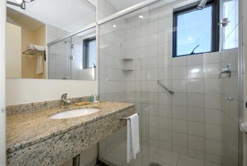 ein Bad mit einem Waschbecken und einer Dusche mit einem Spiegel in der Unterkunft Rede Concept - Hotel Salvador in Salvador