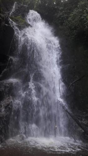 a person standing in front of a waterfall at Ecohotel Bordones in Isnos