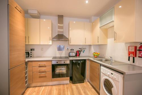 a kitchen with wooden cabinets and a washer and dryer at Grand Canal Square Apartments in Dublin