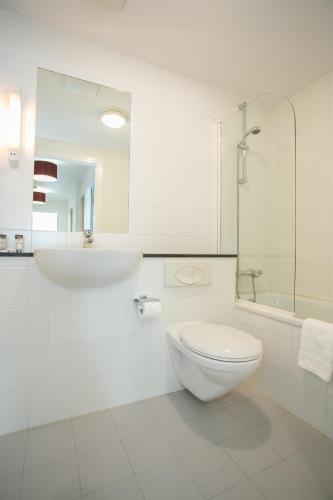 a white bathroom with a toilet and a sink at Grand Canal Square Apartments in Dublin