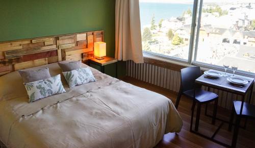 1 dormitorio con cama, mesa y ventana en Patagonia Suite en San Carlos de Bariloche