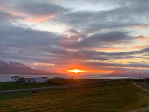 a sunset over a field with the sun in the sky at Sunnuhlid houses in Akureyri
