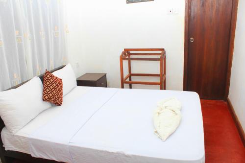 a bedroom with a white bed and a chair at Thal Sewana in Sigiriya
