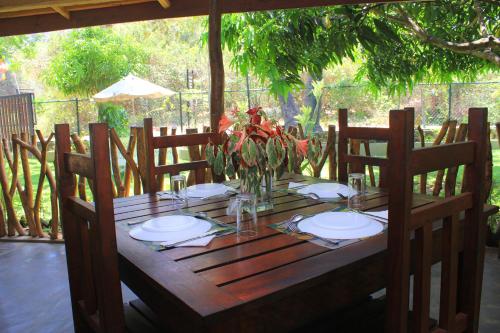 a wooden table with plates and a vase of flowers at Thal Sewana in Sigiriya