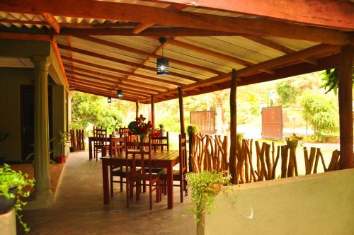 a wooden pergola with tables and chairs on a patio at Thal Sewana in Sigiriya