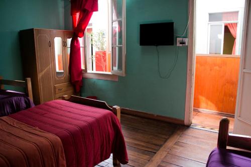 a bedroom with a bed with a red blanket on it at Hostal Tricontinental in Valparaíso
