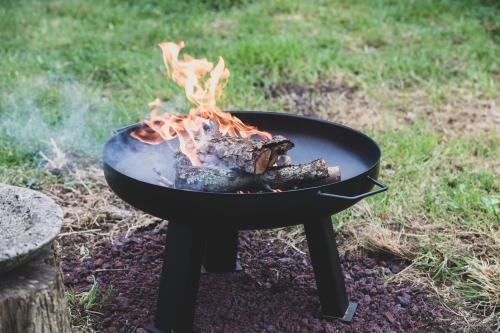 a fire in a grill in the grass at Kakariki Cottage in Papakura