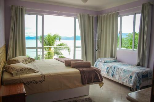 1 dormitorio con cama y ventana grande en Praia Recanto das Pedras, en Governador Celso Ramos