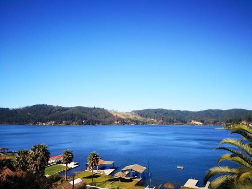 a view of a lake with houses and palm trees at Casa Amanecer Vichuquén in Lago Vichuquen