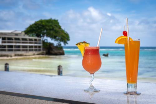 two cocktails sitting on a table on the beach at Yellow Bird Hotel in Christ Church