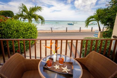 a table on a balcony with a view of the beach at Yellow Bird Hotel in Christ Church