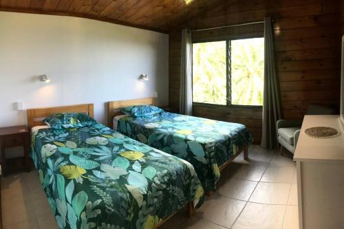 1 dormitorio con 2 camas y una ventana en una cabaña en Pacific views, tranquil location, extra large home, Navy House 1, en Rarotonga