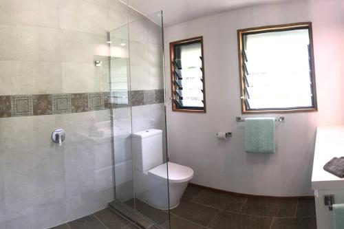 ein Bad mit einem WC und einer Glasdusche in der Unterkunft Pacific views, tranquil location, extra large home, Navy House 1 in Rarotonga