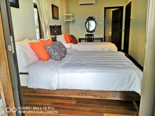 a bedroom with two beds with orange and white pillows at Kairos Villa in Seremban