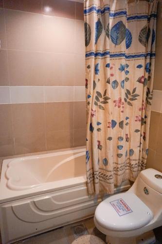 a bathroom with a toilet and a shower curtain at Crowne Garden Hotel in Cebu City