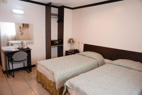 a hotel room with two beds and a desk at Crowne Garden Hotel in Cebu City