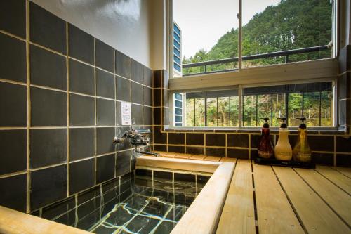 a bathroom with a shower with a window and a tub at Shirakabe in Izu