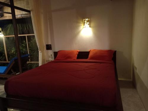 a bedroom with a bed with red sheets and a window at Menjangan View in Banyuwedang