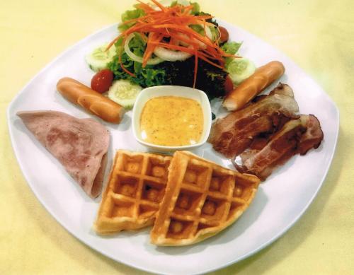 a plate of food with waffles and meat and a salad at VC@Suanpaak Boutique Hotel & Service Apartment in Chiang Mai
