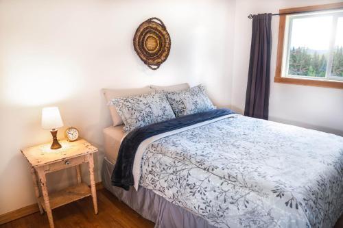 1 dormitorio con 1 cama y 1 mesa con lámpara en Willow Grove B&B Inn, en Horsefly
