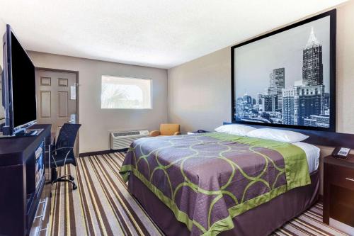 a hotel room with a bed and a flat screen tv at Super 8 by Wyndham Stockbridge in Stockbridge
