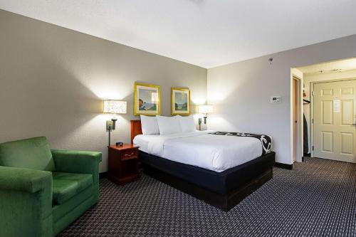 a hotel room with a bed and a green chair at La Quinta Inn by Wyndham Ft. Lauderdale Tamarac East in Fort Lauderdale