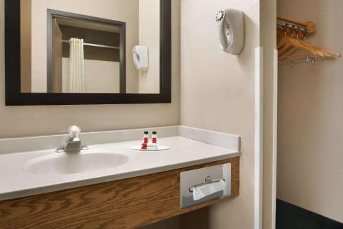 a bathroom with a white sink and a mirror at Super 8 by Wyndham Akron S/Green/Uniontown OH in Uniontown