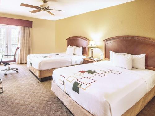 a hotel room with two beds and a chair at La Quinta by Wyndham Marble Falls in Marble Falls