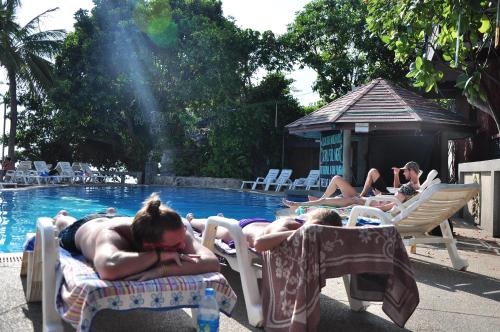 a group of people laying on lawn chairs by a pool at Coral Resort & Bungalows in Haad Rin