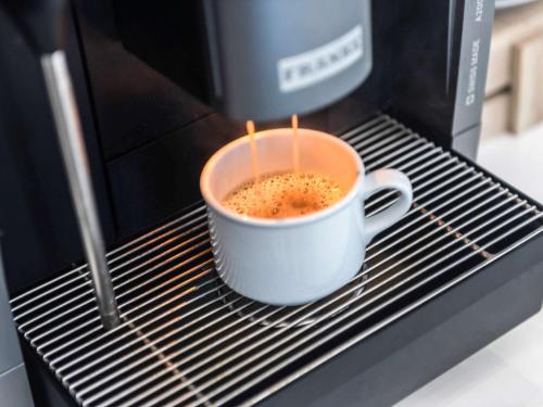 a cup of coffee sitting in a microwave at Mercure Singapore On Stevens in Singapore