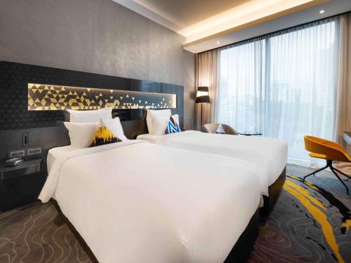 a large white bed in a hotel room at Novotel Singapore On Stevens in Singapore